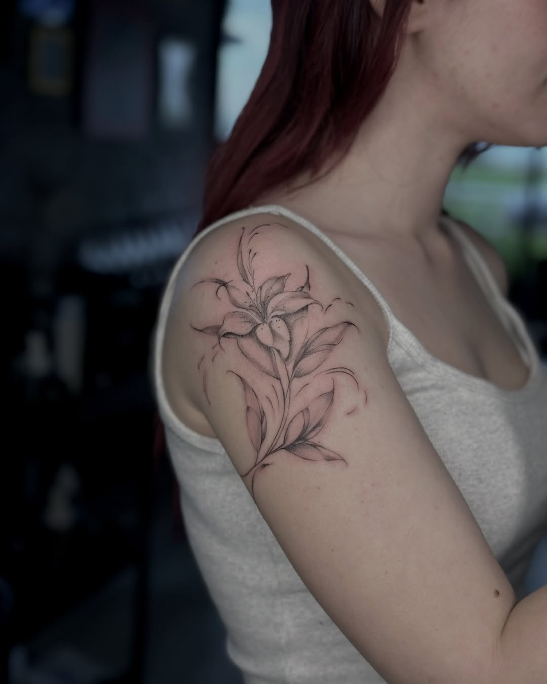 Omuz zambak çiçeği ve yapraklar dövmesi — yumuşak fine line kadın işi | Titan Ink Gallery Samsun